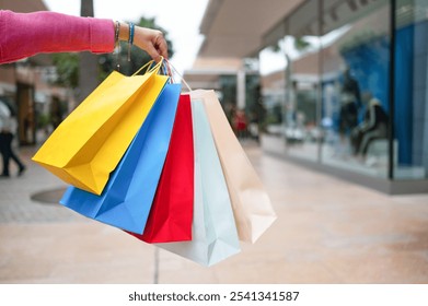 Woman holding colorful shopping bags at the mall, enjoying a day of retail therapy - Powered by Shutterstock