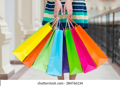 Woman holding colourful shopping bags at the mall. - Shutterstock ID 284766134