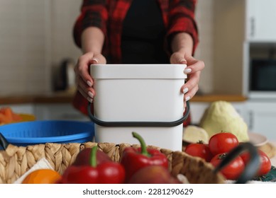 Woman holding compost bin. Female cooking dinner at home and recycling organic waste in a bokashi container. Person using ferment to decompose food leftovers into fertilizer - Powered by Shutterstock