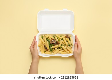 Woman holding container with delicious food on color background