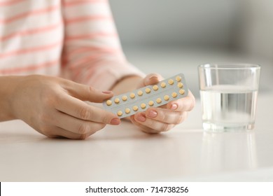 Woman holding contraceptive pills at table