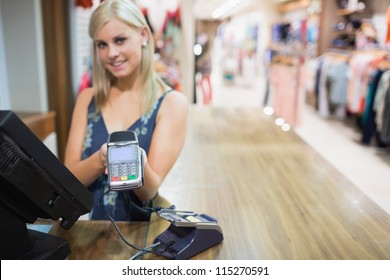 Woman Holding Credit Card Mahine In Clothing Store