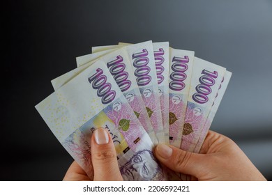 Woman holding a crown in her hands on a black background. European currency, Czech money.
