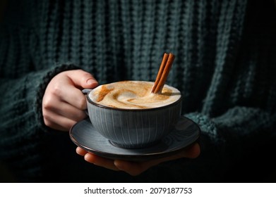 Woman Holding Cup Of Cappuccino With Cinnamon Sticks