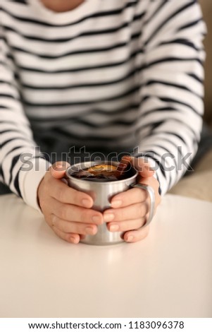 Woman holding cup of delicious mulled wine at table, closeup