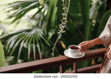 Woman Holding Cup Of Hot Steaming Drink Tea On The  Balcony With Tropical View