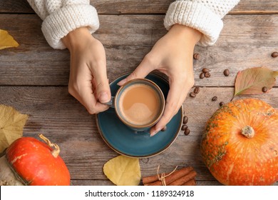 Woman Holding Cup With Pumpkin Spice Latte On Wooden Background, Top View