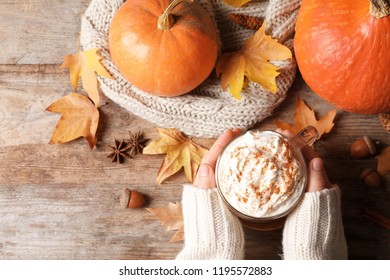 Woman Holding Cup With Pumpkin Spice Latte On Wooden Table, Flat Lay