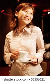 Woman holding cup and saucer, smiling