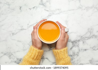 Woman Holding Cup With Sea Buckthorn Tea At White Marble Table, Top View