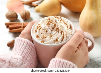 Woman Holding Cup With Tasty Pumpkin Spice Latte At White Marble Table, Closeup