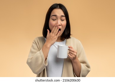 Woman holding cup of tea or coffee in hand at morning, sleepy and tired, wants to sleep, while yawning. Night Owl type concept 