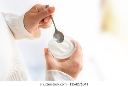 Woman Holding A Cup Of Yogurt And Spoon In Hand. Yogurt Made From Milk Fermented By Added Bacteria, Often Sweetened And Flavored.