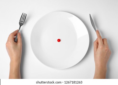 Woman Holding Cutlery Near Plate With Weight Loss Pill On White Background, Top View