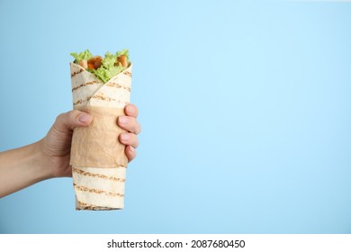 Woman holding delicious chicken shawarma on light blue background, closeup. Space for text