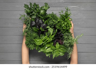 Woman holding different fresh herbs in basket at light grey wooden table, top view - Powered by Shutterstock