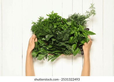 Woman holding different fresh herbs in basket at white wooden table, top view - Powered by Shutterstock