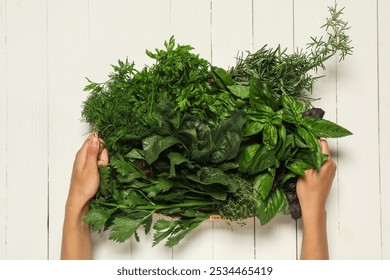 Woman holding different fresh herbs in basket at white wooden table, top view - Powered by Shutterstock