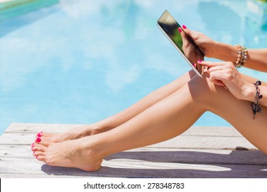 Woman holding digital tablet outdoors by the swimming pool - Powered by Shutterstock