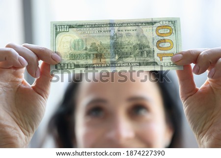 Woman holding dollar bill and looking at it with watermarks closeup. Counterfeiting money concept