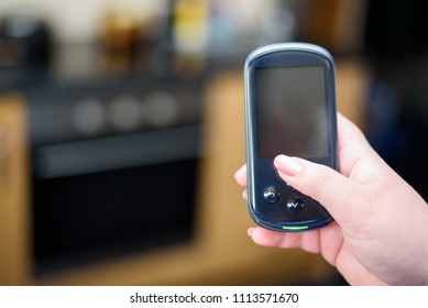 Woman Holding A Domestic Energy Smart Meter Unit In A Kitchen