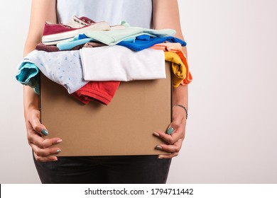 Woman holding a donate box. Donation box for giving. Sharity social activity. Cardboard box with clothes for charity. Female volunteer holding donations. Case full of clothing for giving. Help poor.