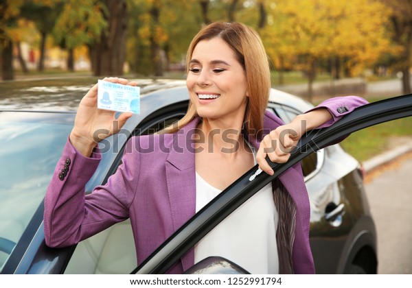 Woman holding
driving license near open
car