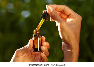 A woman holding a dropper with an oil product