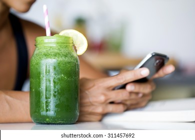 Woman Holding Electronic Tablet While Drinking A Green Detox Juice.