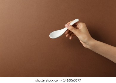 Woman holding empty miso soup spoon on color background, closeup. Space for text