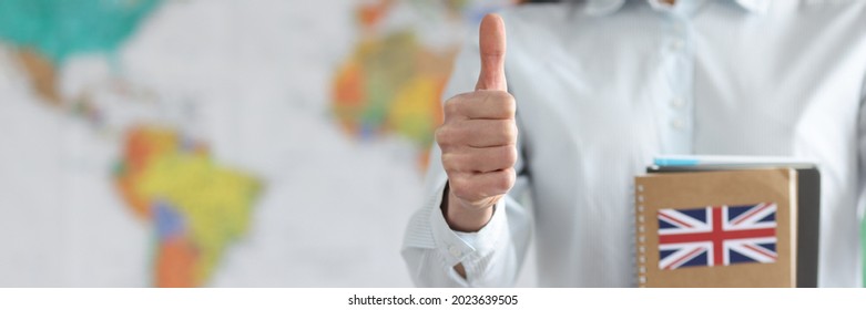 Woman Holding English Textbooks On Background Of World Map And Showing Thumb Up Closeup