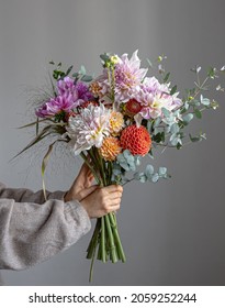 A woman is holding a festive bouquet with chrysathemum flowers in her hands.