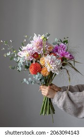 A woman is holding a festive bouquet with chrysathemum flowers in her hands.