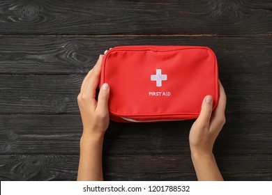 Woman Holding First Aid Kit On Dark Table, Top View