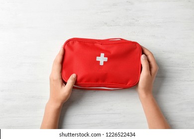 Woman Holding First Aid Kit On Wooden Background, Top View