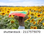 Woman holding flag of Lithuania in a sunflowers field. Back view. Lithuanian Flag Day. Independence restoration Day. Travel and love Lithuania concept. Selective focus.