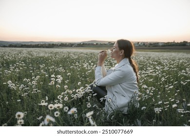 A woman is holding a flower and smelling it. Concept of peace and tranquility, as the woman is surrounded by nature and taking a moment to appreciate the beauty of the flower. - Powered by Shutterstock