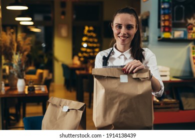 Frau, die Lebensmittel in Papiertüten hält, die für die Lieferung vorbereitet sind
