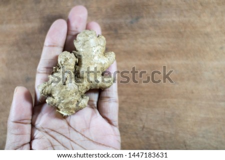 Woman Holding Fresh Ceylon Ginger Root on Wooden Background.