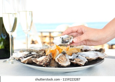 Woman Holding Fresh Oyster Over Plate, Focus On Hand