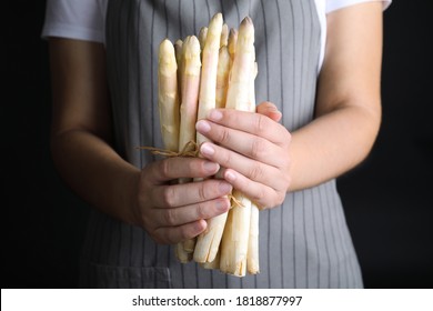 Woman holding fresh white asparagus on black background, closeup