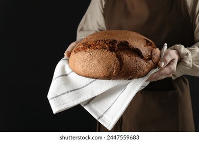 Woman holding freshly baked bread on black background, closeup - Powered by Shutterstock