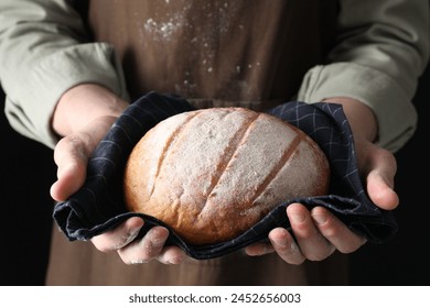 Woman holding freshly baked bread on black background, closeup - Powered by Shutterstock