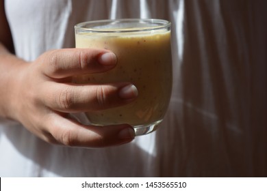 Woman holding a fruit smoothie, freshly made with banana and nectarine, close-up
