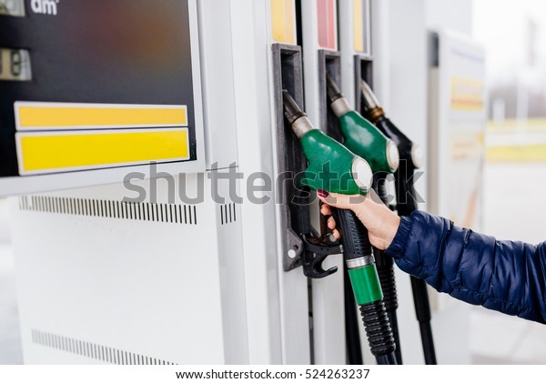 Woman\
holding a fuel nozzle on the gasoline\
station