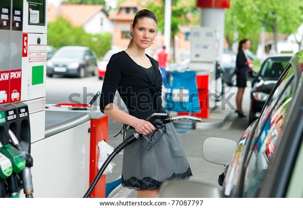 woman\
holding fuel nozzle and refuel car in gas\
station