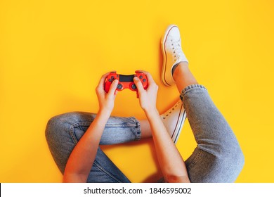 Woman Holding Gamepad In Her Hands In Against Of A Yellow Background. Promotion Of Women's Esports. Advertising Of Esports Equipment. Flat Lay. Place For Text.