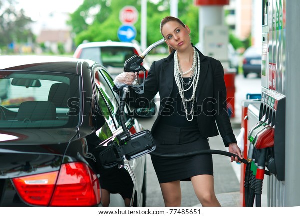 woman\
holding gas nozzle as gun pointed to her\
head