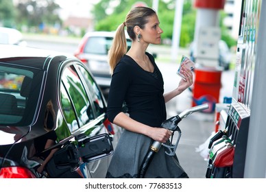 Woman Holding Gas Nozzle And Money In Gas Station