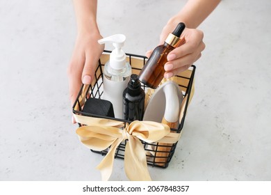 Woman Holding Gift Basket With Cosmetics On Light Background